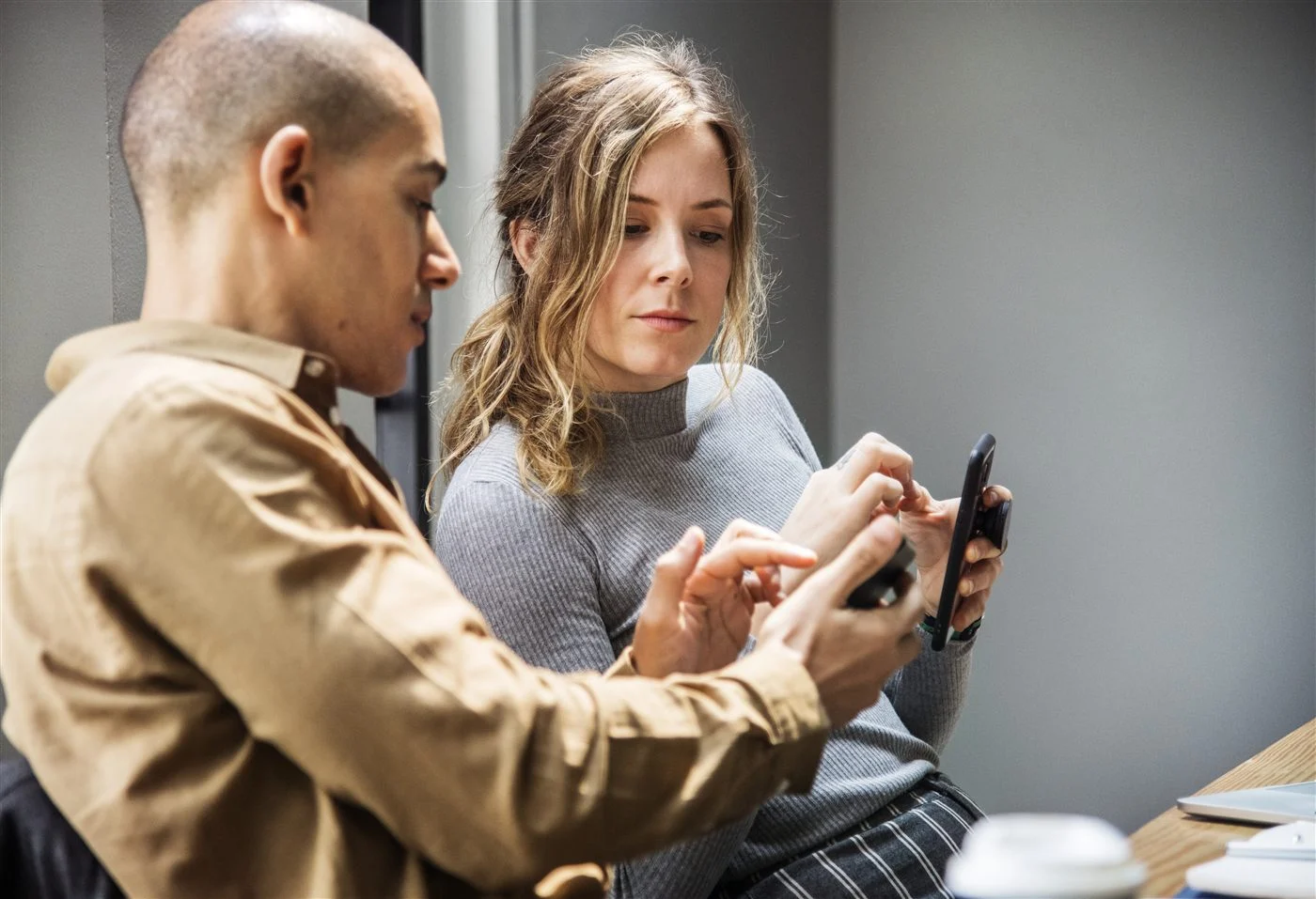 Deux personnes discutent d’un projet, téléphone en main